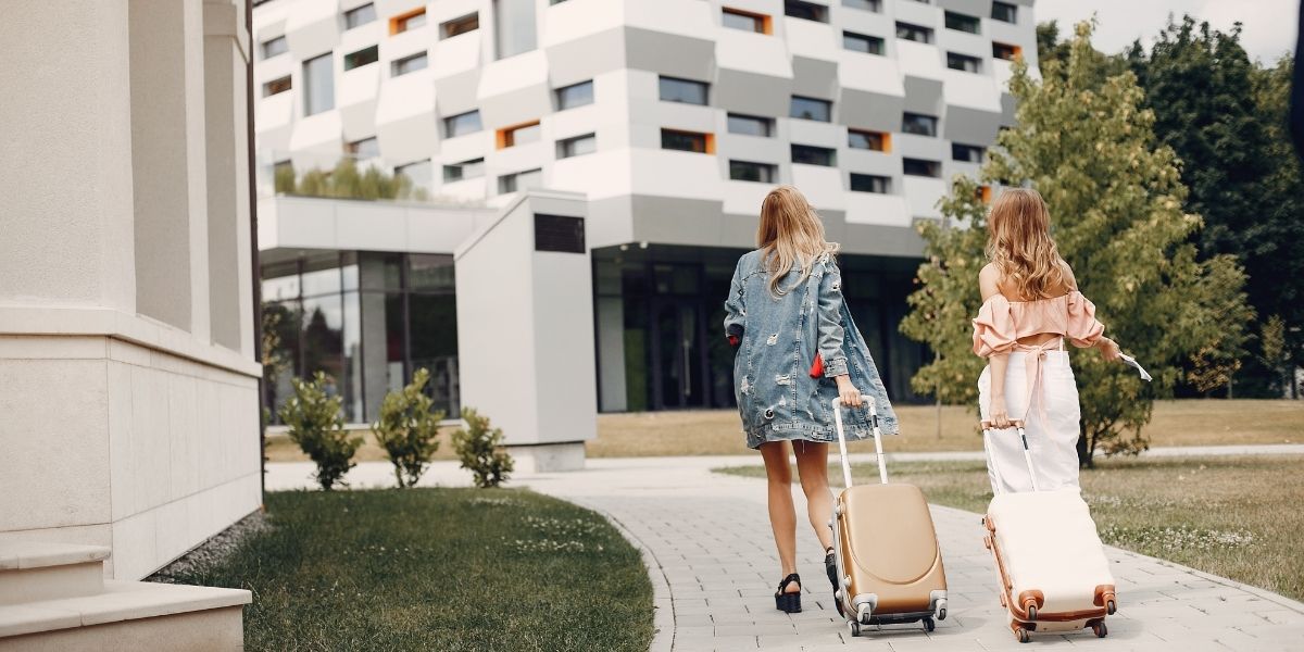 Dos mujeres con equipaje accediendo a un edificio