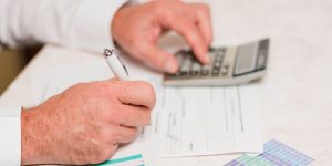 Persona usando calculadora y rellenando formularios