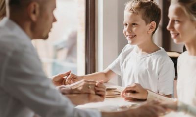 Dos niños en una oficina con dos adultos que les cogen de las manos