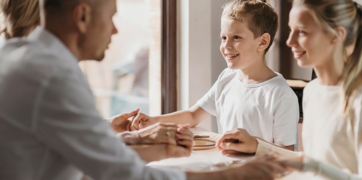 Dos niños en una oficina con dos adultos que les cogen de las manos