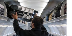 Un pasajero colocando su maleta de cabina en el compartimento superior