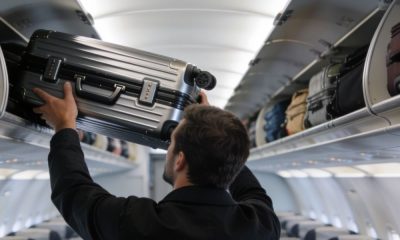 Un pasajero colocando su maleta de cabina en el compartimento superior