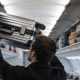 Un pasajero colocando su maleta de cabina en el compartimento superior