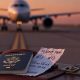 Maleta, billete y avión de fondo