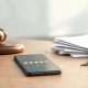 Mazo judicial junto a un teléfono móvil y documentos laborales en un escritorio.