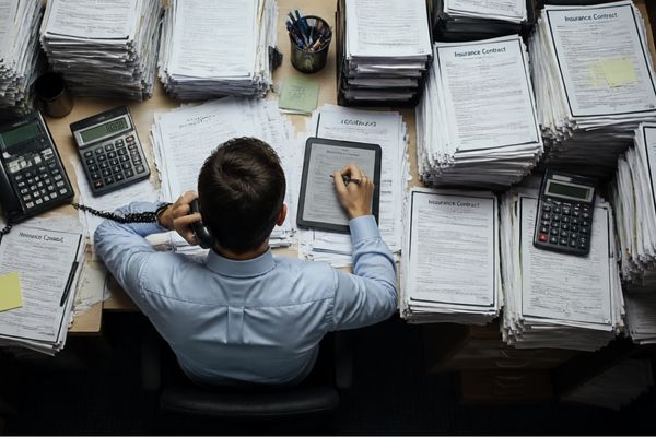 Una persona con muchos expedientes en la mesa