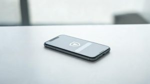 Teléfono inteligente sobre una mesa de oficina mostrando una interfaz de seguridad para mensajes de texto.
