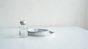 Viales médicos genéricos y una cinta métrica sobre un escritorio clínico.
