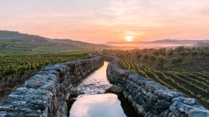 Canal de riego tradicional de piedra con agua fluyendo en un paisaje agrario