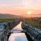 Canal de riego tradicional de piedra con agua fluyendo en un paisaje agrario