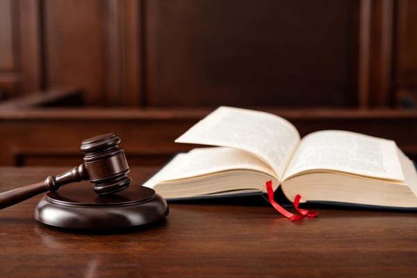 Mazo judicial junto a un libro de leyes abierto en una sala de vistas.