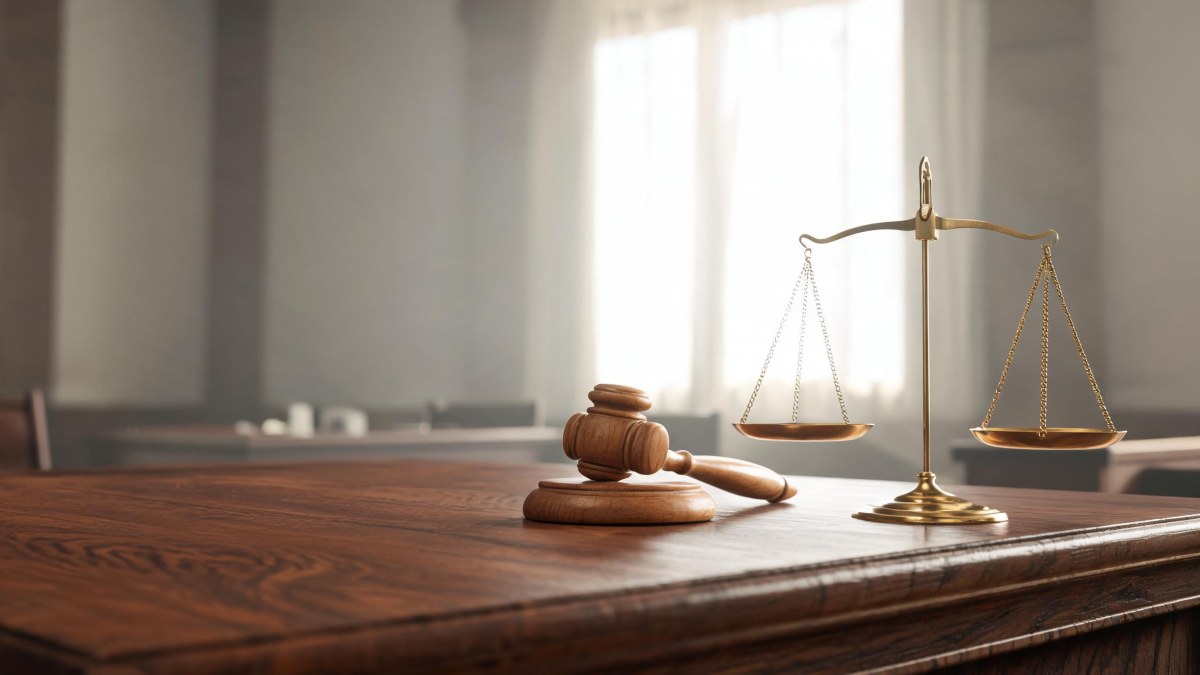 Mazo judicial de madera y balanza de la justicia sobre una mesa de despacho jurídico
