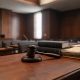 Mazo de juez y códigos penales sobre una mesa de madera en una sala judicial.