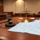 Mazo judicial sobre una mesa junto a planos técnicos en un entorno institucional.