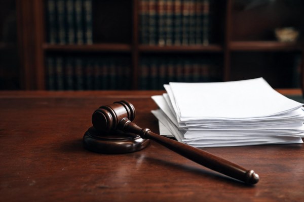 Mazo judicial de madera junto a documentos contractuales en un despacho jurídico.