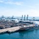 Vista general de terminal de contenedores y dársena portuaria con grúas y muelles.