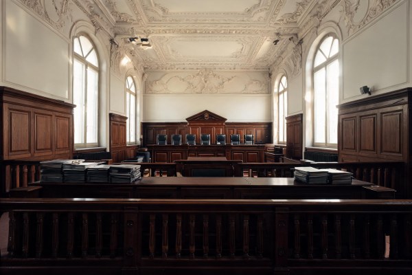 Sala de vistas de un tribunal de justicia con estrados de madera y carpetas procesales.