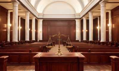 Interior solemne de una sala de tribunal con estrado de madera y columnas.