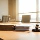 Documentos corporativos y mazo judicial sobre una mesa de reuniones.
