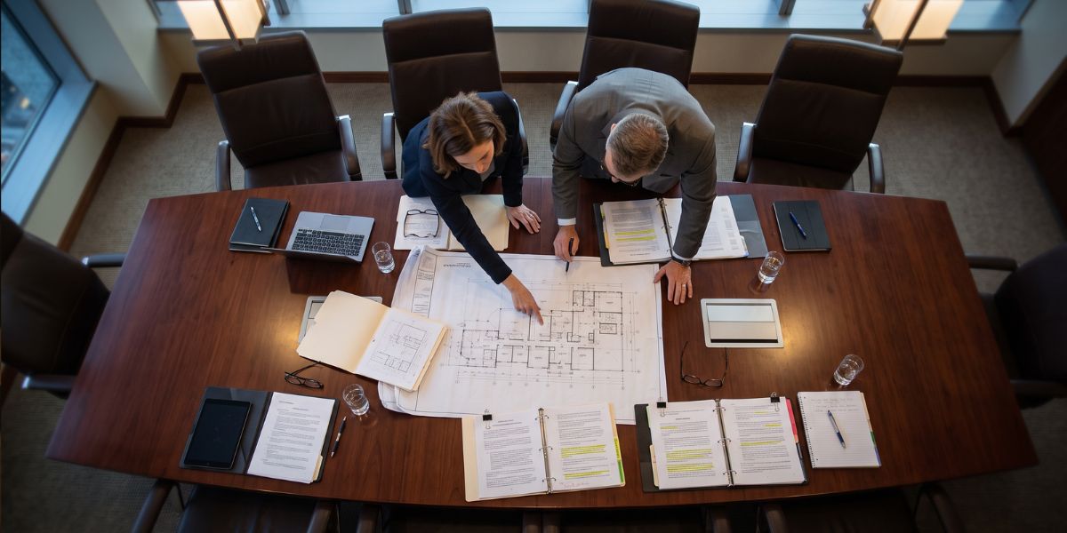 Dos abogados con planos de una vivienda