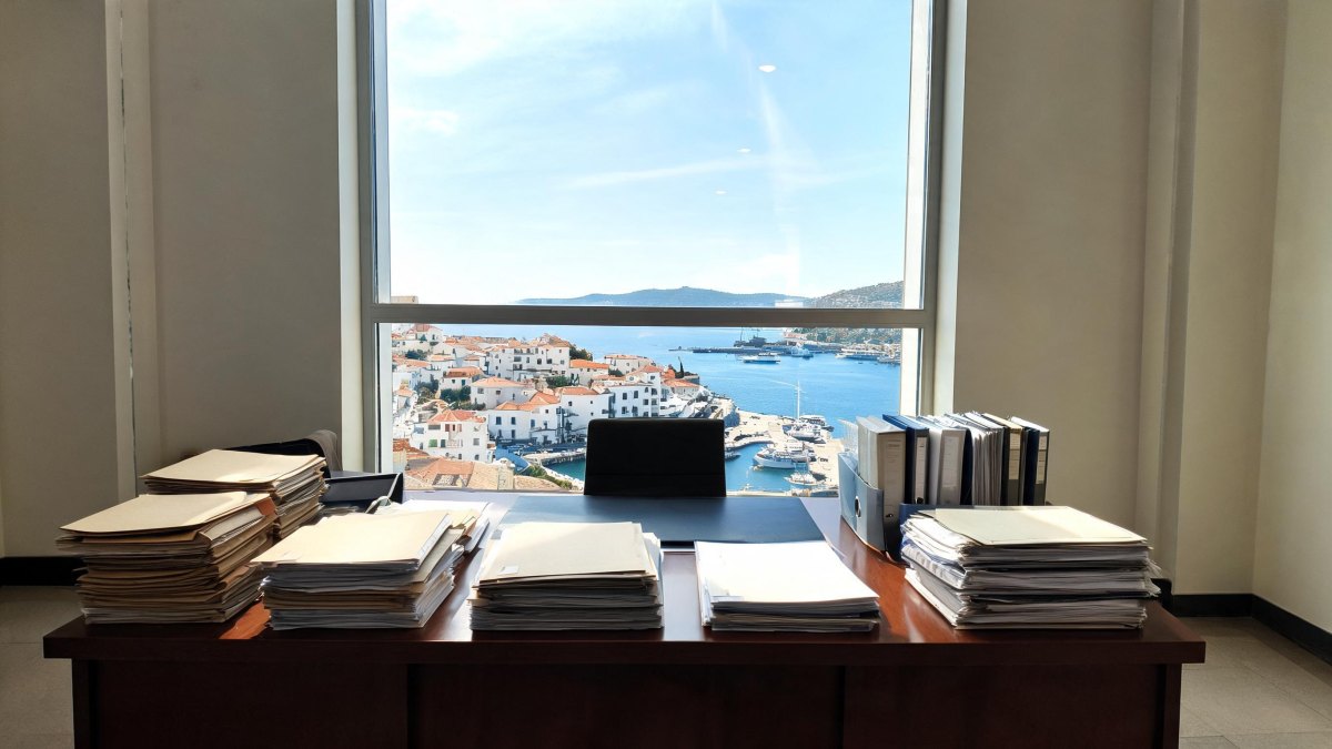 Carpetas y documentos administrativos sobre un escritorio de oficina gubernamental con iluminación natural.