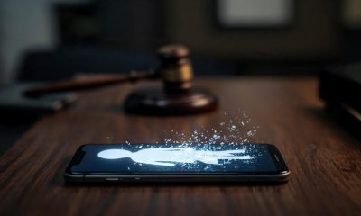 Teléfono inteligente sobre una mesa mostrando una figura digital abstracta junto a un mazo judicial desenfocado
