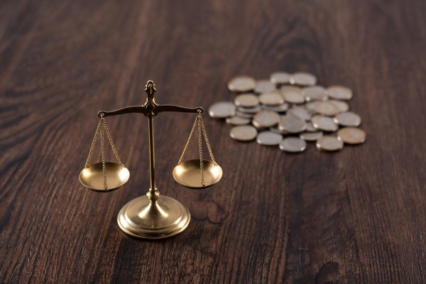 Balanza de la justicia junto a monedas en una mesa de despacho jurídico.