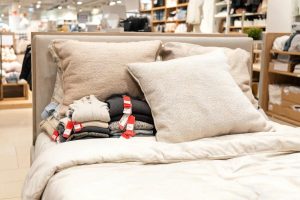 Prendas rebajadas escondidas entre las almohadas de una cama de exposición en una tienda