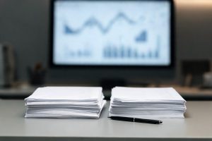 Detalle de documentos bancarios y pantalla en un entorno financiero de oficina.