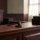 Sala de vistas judicial en un tribunal penal con códigos y mazo de madera sobre la mesa.