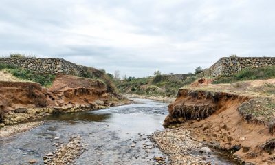 Cauce de un arroyo con erosión natural en sus márgenes y obras de contención