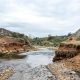Cauce de un arroyo con erosión natural en sus márgenes y obras de contención