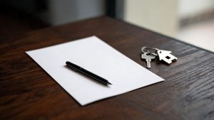 Contrato de arrendamiento con un bolígrafo y llaves de vivienda sobre una mesa de madera