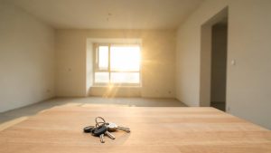 Manojo de llaves sobre una mesa en una habitación vacía iluminada por luz natural.