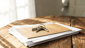 Llaves de vivienda y documentos sobre una mesa en un entorno doméstico.
