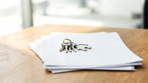 Llaves de vivienda sobre documentos contractuales y jurídicos en una mesa.