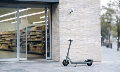 Patinete eléctrico situado en un espacio comercial junto a una cámara de seguridad.