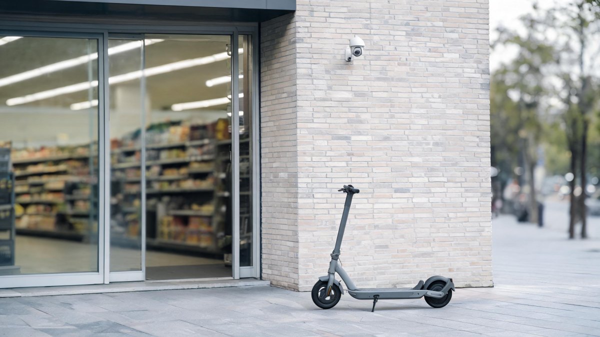 Patinete eléctrico situado en un espacio comercial junto a una cámara de seguridad.
